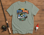 Sage green t-shirt with fishing graphic and text 'Fish More Worry Less' on a wooden surface with fishing equipment.

