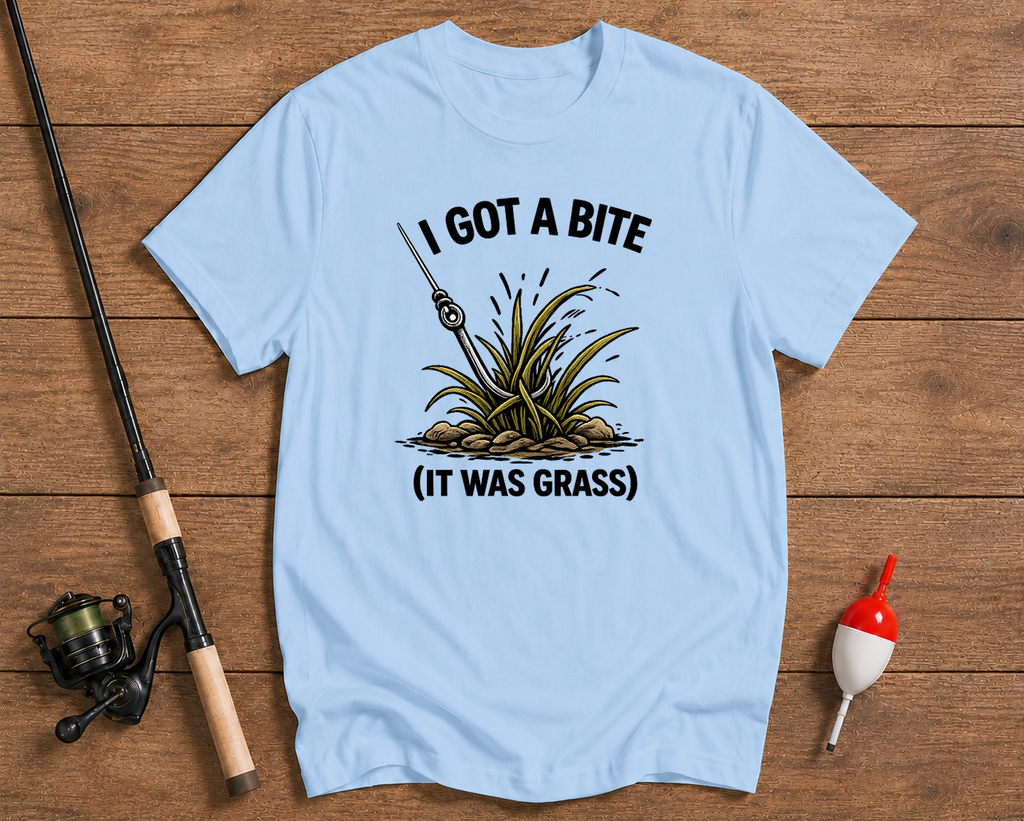 Light blue t-shirt with fishing graphic and text on a wooden surface with fishing equipment.

