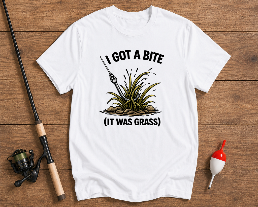 White t-shirt with fishing graphic and text on a wooden surface with fishing equipment.

