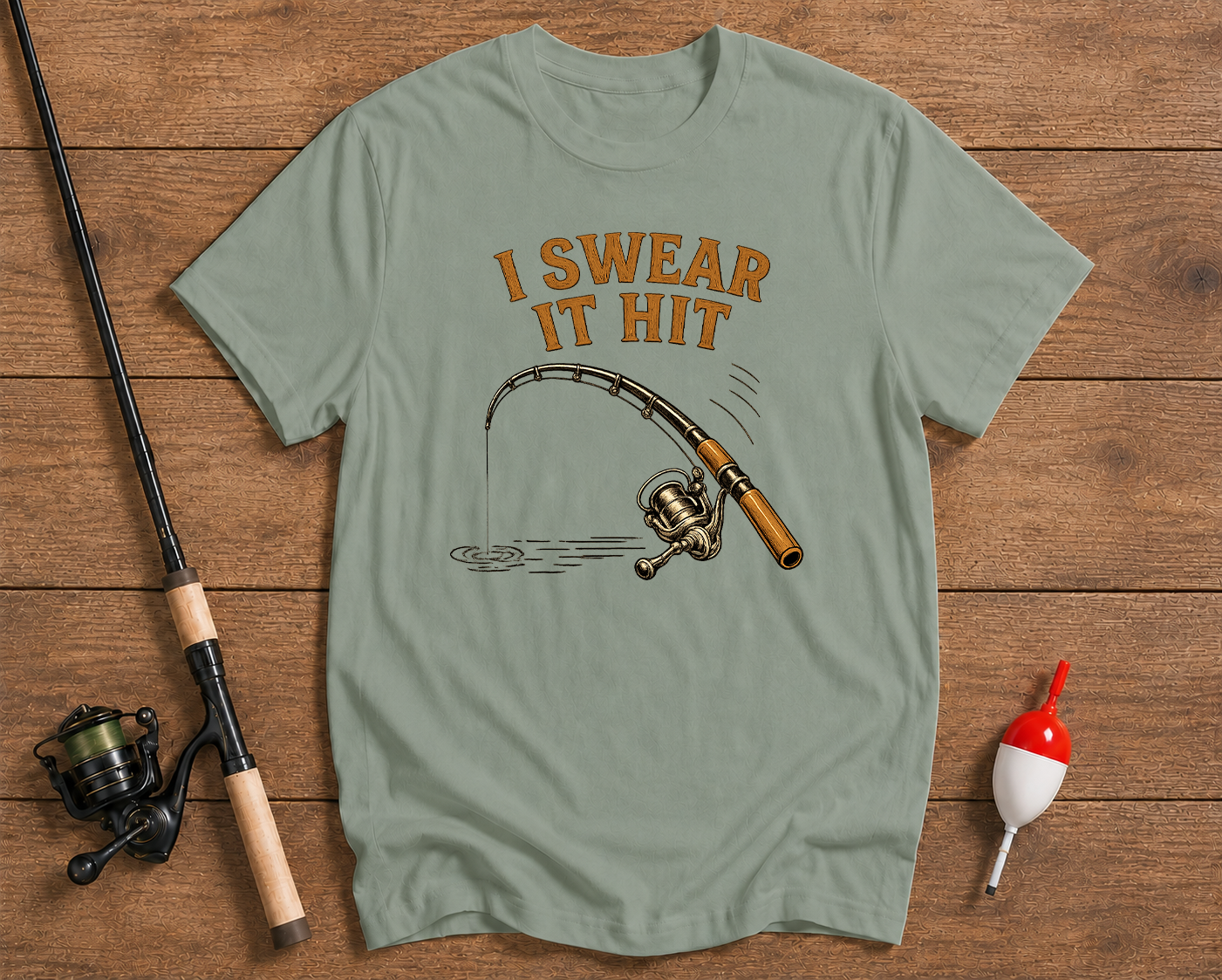 I Swear It Hit fishing graphic tee in sage green featuring an angler fishing rod illustration by Funky Fish Club