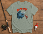 Green t-shirt with fish graphic and 'Nice Try' text on a wooden surface with fishing equipment.

